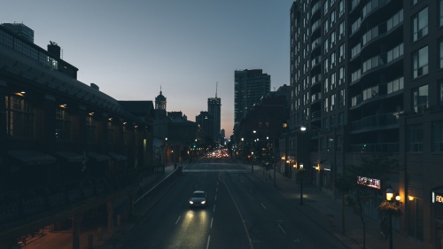 A car driving down a dark street in a big city.