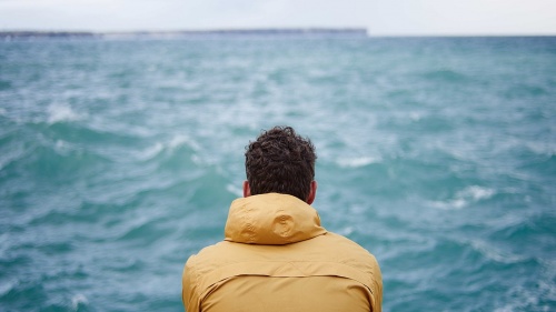 A man watching the waves on a lake.