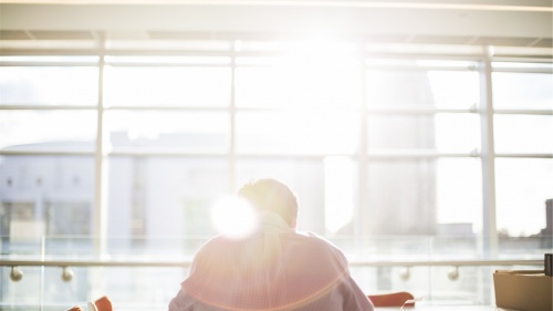 A person sitting at a table with sun rays coming in from a window.