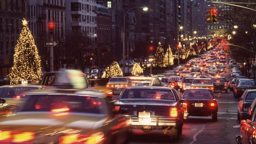 A busy city street lined with Christmas decorations and lit trees.