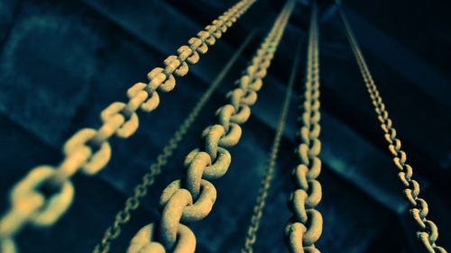 Old chains hanging down from a dark ceiling.