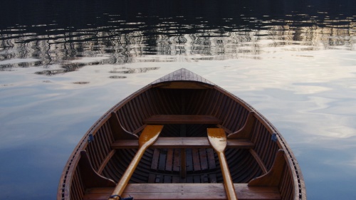 An empty wooden boat with two wooden oars.