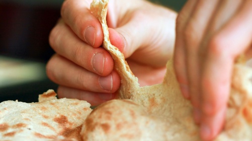 A person pulling apart some flat bread,