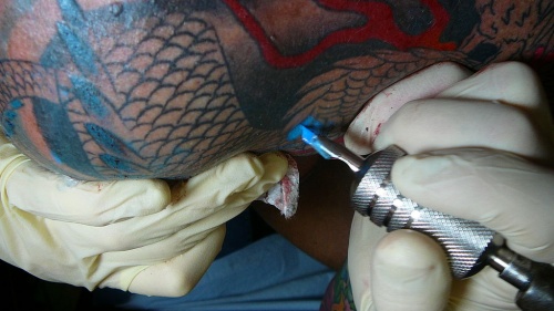 Tattooing a design on a person&#039;s arm.