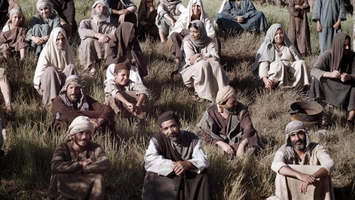 People in robes sitting in the grass looking at an unseen speaker