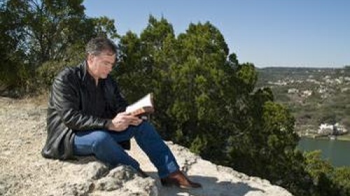 A man reading a Bible sitting outside.