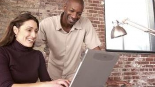 A man and woman working together on a laptop.