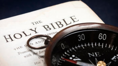 A compass on top of a Bible.