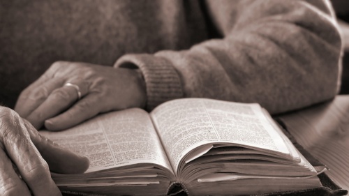 An older person reading a Bible.