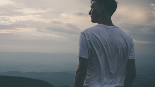 A young man looking over the vista of a mountain.