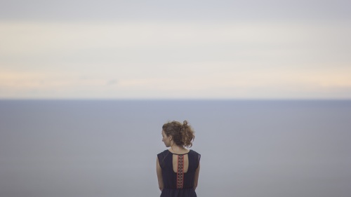 A young women looking at the ocean.