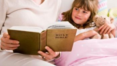 Mother reading Bible to child in bed - Teaching Youth Religious Values