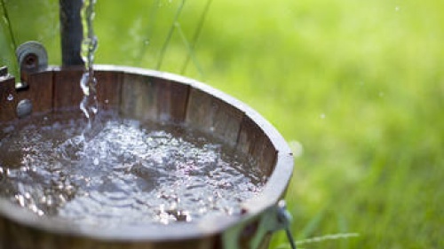 Water pouring into a wood bucket.