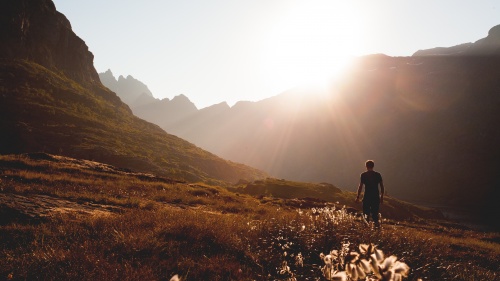 A person walking on a path up to a mountain peak.