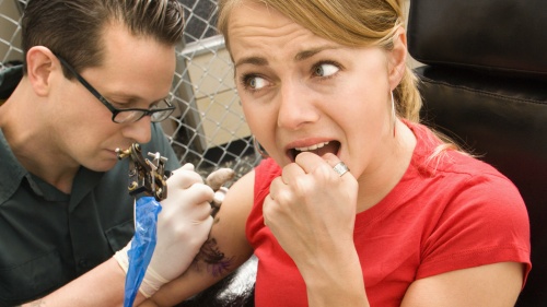 A young woman getting a tattoo.