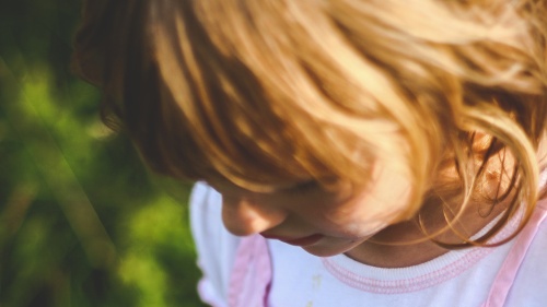 A little girl looking down at the ground.