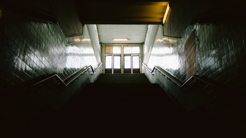 Dark stairs leading up to doors where light is coming through.