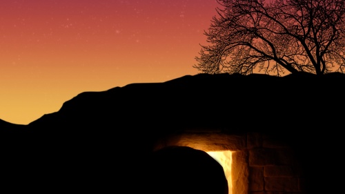 A tomb cut out of rock with a round stone next to the entrance.