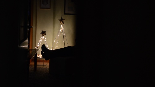 A person sitting in a dark room with Christmas lights.