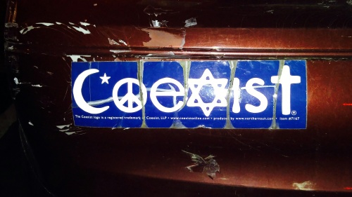 A coexist sticker on the bumper of a car.