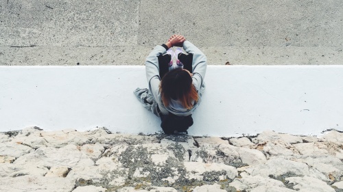 A woman sitting on a sidewalk.