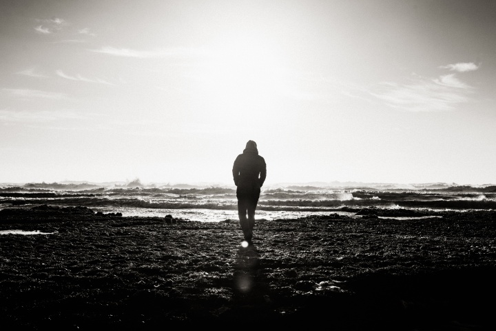 A main walking by the ocean shoreline.