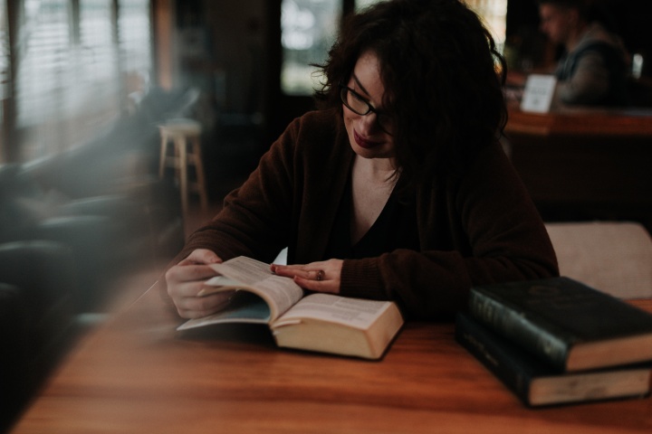 a woman sitting at a table reading a Bible