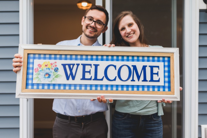 a man and a woman holding a sign that reads "welcome"