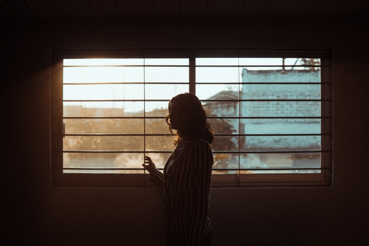 a woman standing in a dark room with a window in the background