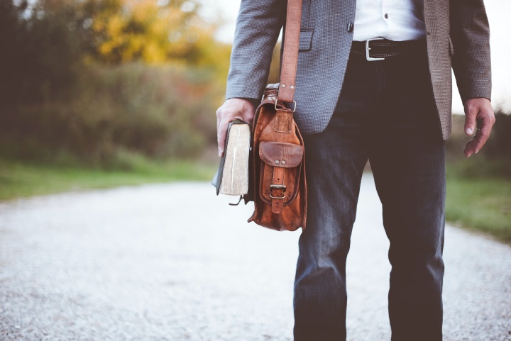 a man in a suit standing in the road and holding a Bible