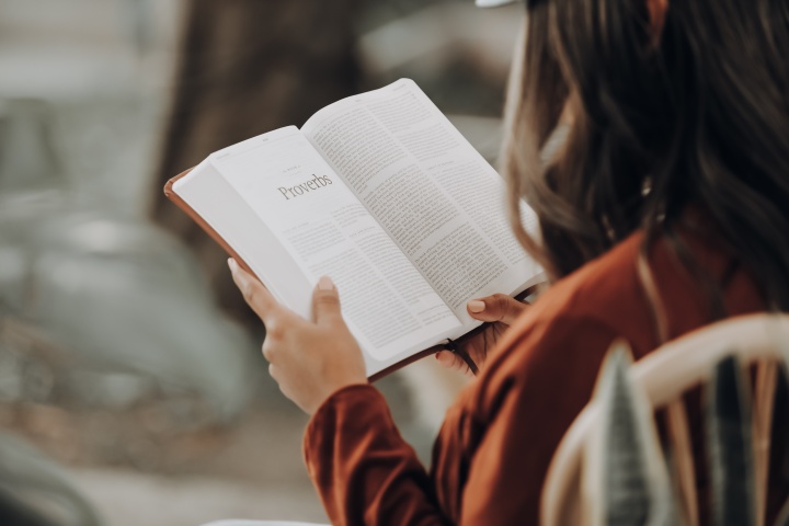 a woman sitting with an open Bible in her hands