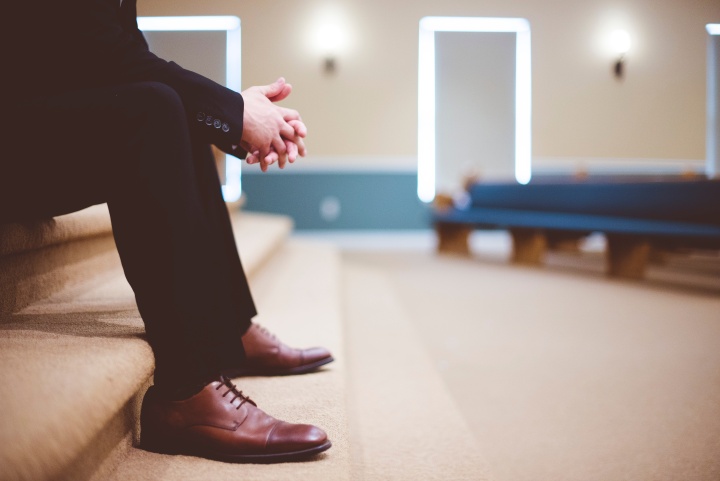 a man wearing a suit sitting on indoor steps