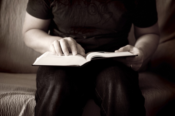 A Bible on the lap of a man.