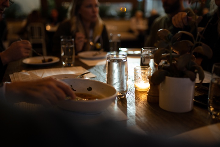 a group of people gathered around a dinner table, lit by candlelight
