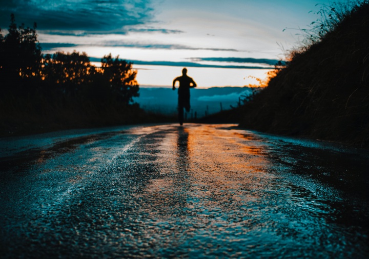 Silhouette photo of a person running on road.