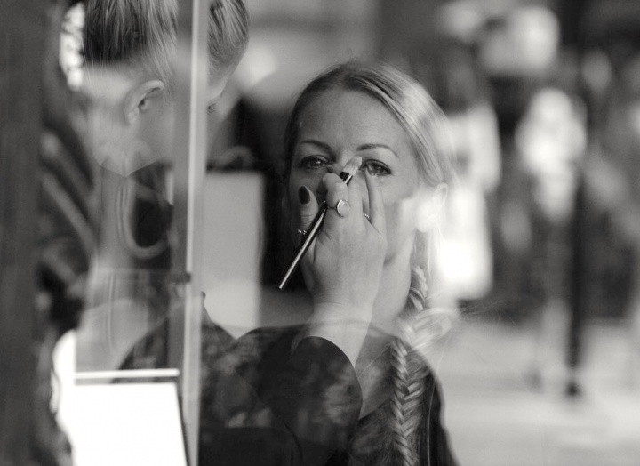 A woman getting makeup put on her in a salon. 