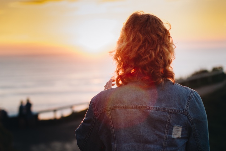 A woman looking at sunset over a body of water.