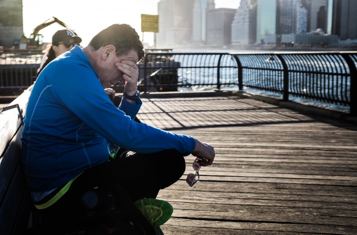 A man sitting on a dock with the water near by. 