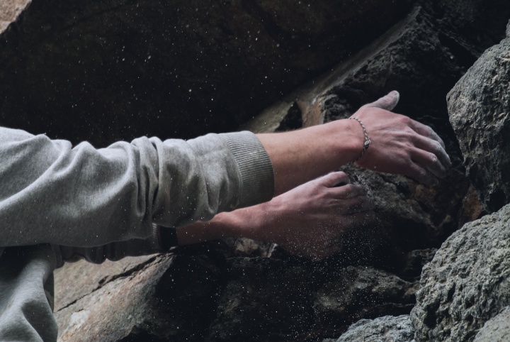 A rock climber's hands gripping onto rock cliff.