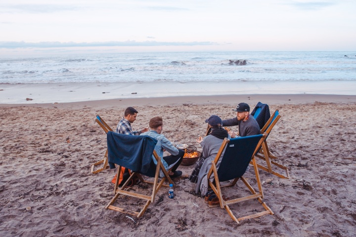 A group of friends around a campfire on the beach.