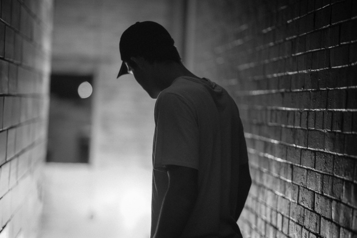 A man walking in a hallway surrounded by brick walls.