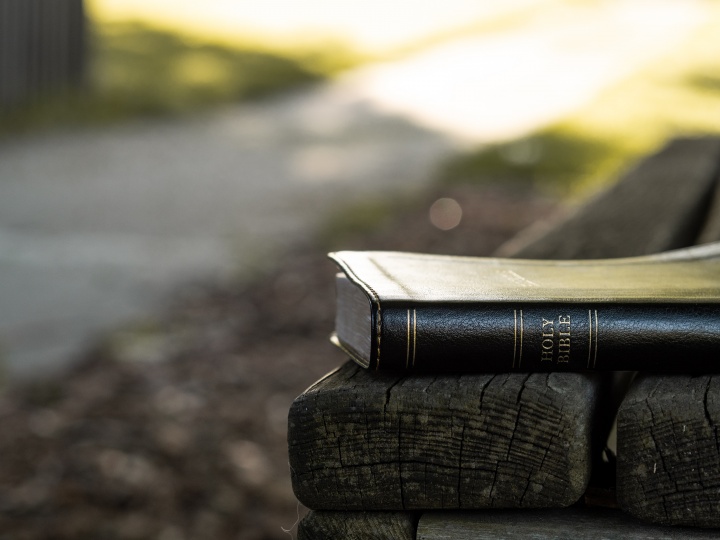 A Bible laying on a park bench.