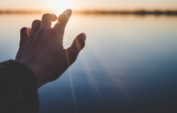 A hand reaching out over water. 