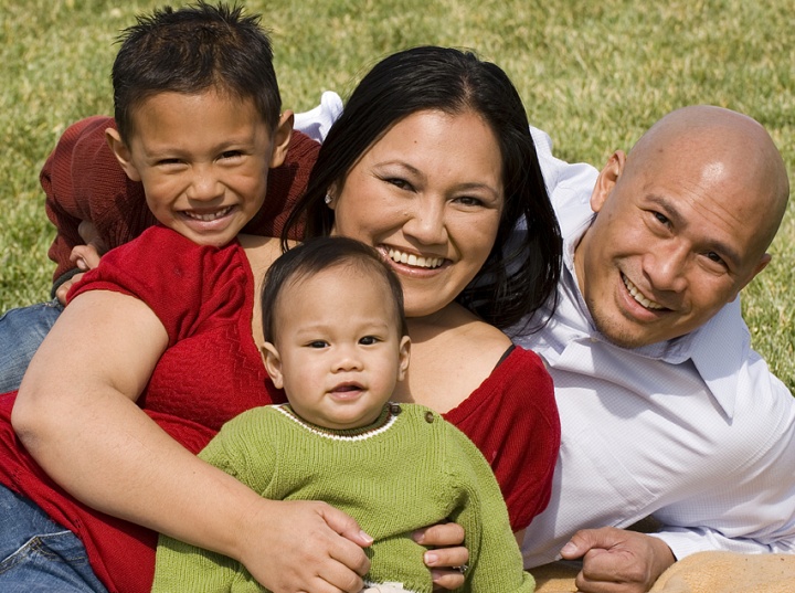 A family lying down on a blanket.