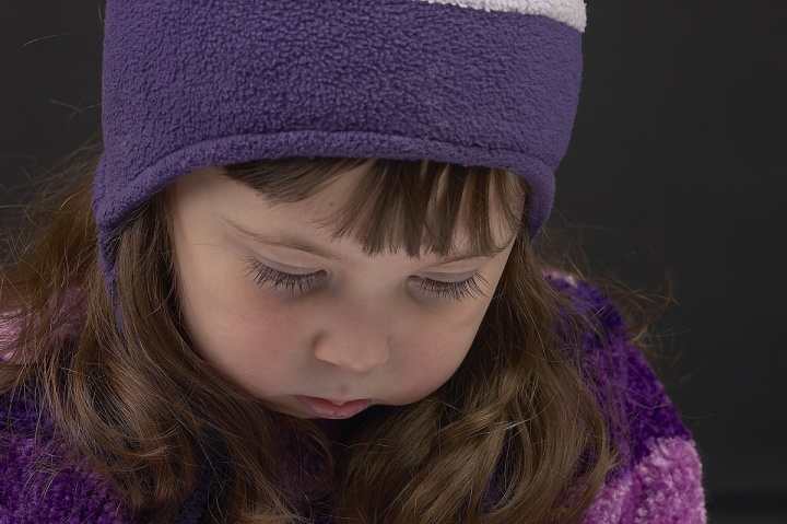 A little girl with a sad expression on her face looking down.