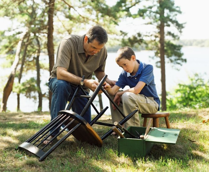 A father and son repairing a broken chair together.
