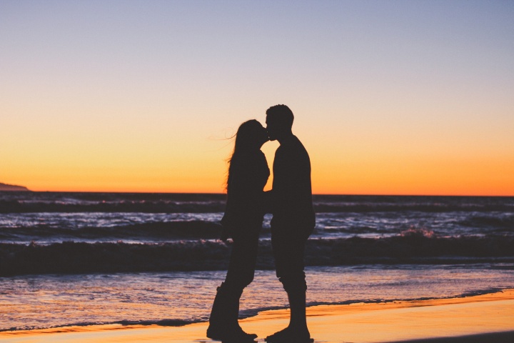 Husband and wife kissing on the beach.