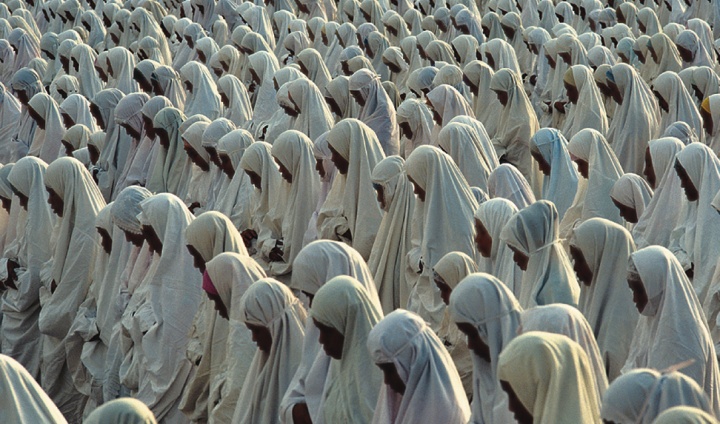 Muslim women pray, bowing toward Mecca.