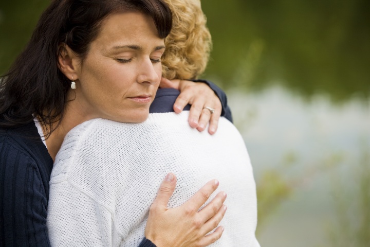 A woman hugging a grieving woman.
