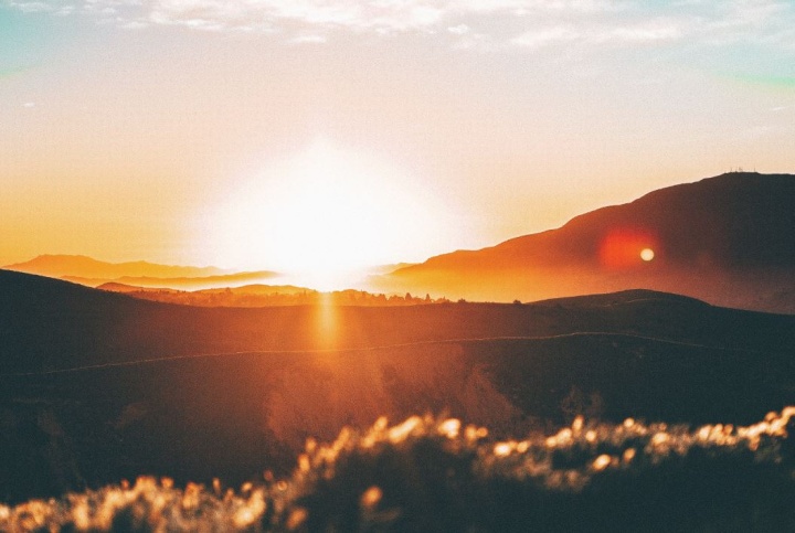 Sun rays shining over hills.